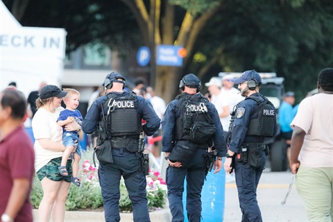 back of three police officers talking to adult holding a child